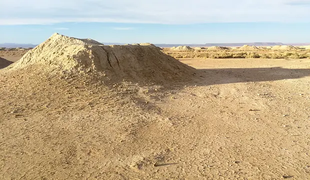 Alineación de pozos verticales de una khettara en el desierto de Marruecos, visibles como montículos sobre la superficie