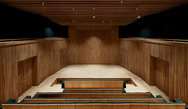 Auditorio del museo Yves Saint Laurent de Marrakech, con paredes y techo revestidos de madera y gradas orientadas hacia el escenario